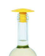 A close-up of a clear glass bottle neck with a yellow lion Whine Stopper teether, shown against a white background.