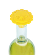 A bright yellow lion-shaped bottle stopper with a smiling face, shown on the neck of a clear glass bottle containing a pale yellow liquid, isolated on a white background.
